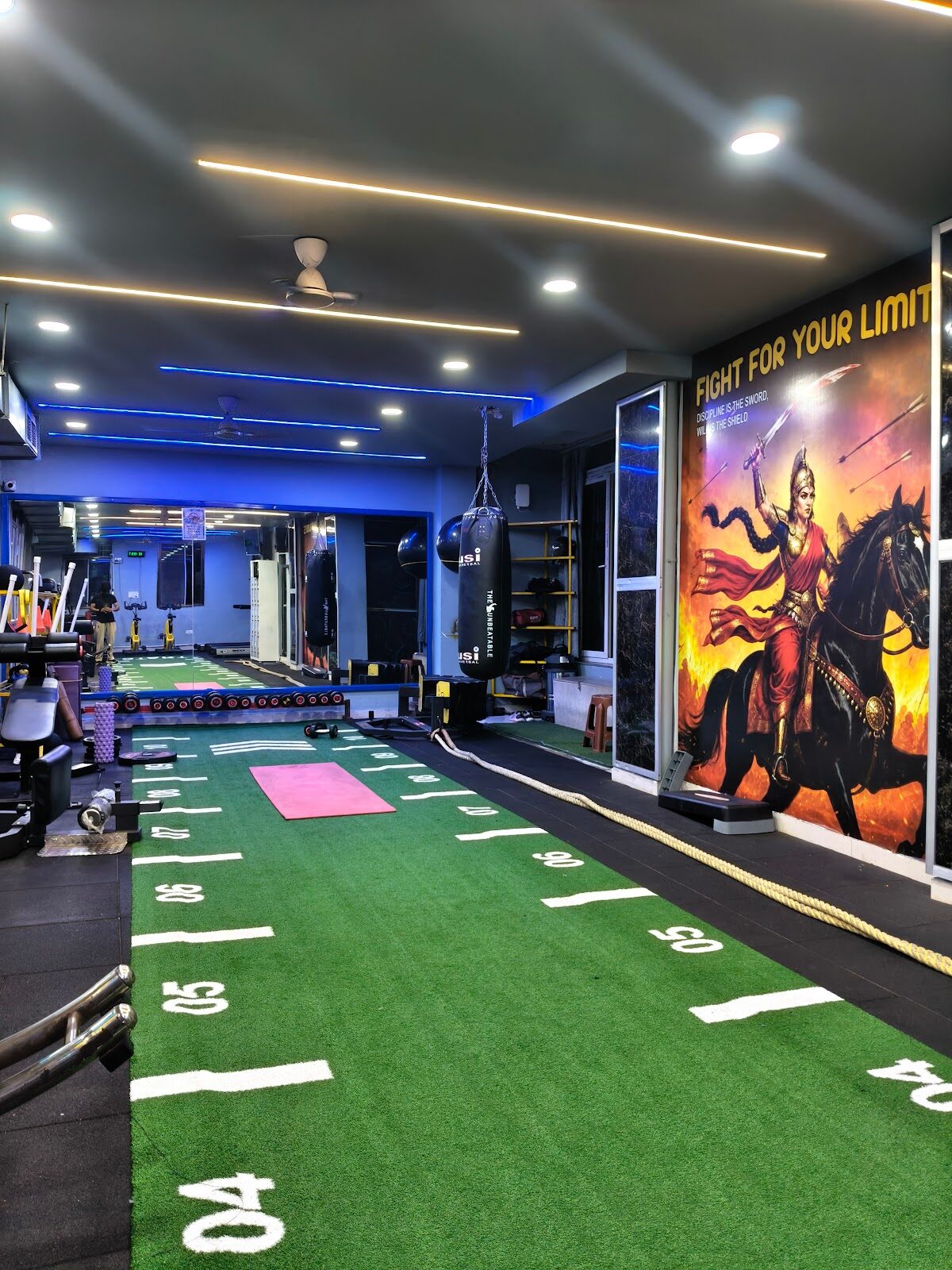 Soul Fitness gym floor: sprint turf track, yellow machines and the Fight For Your Limit mural